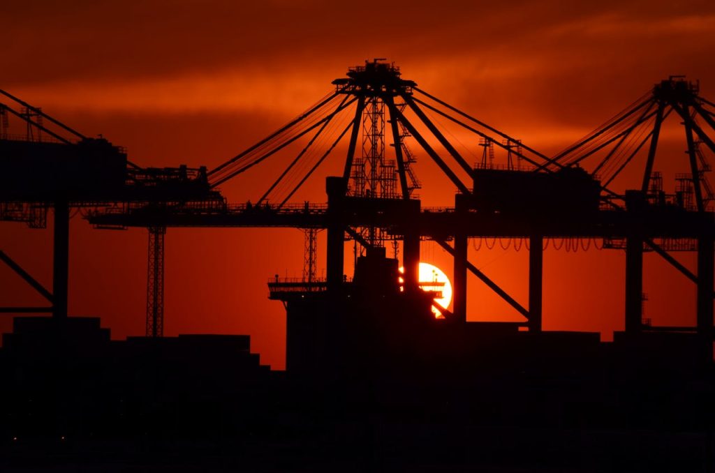 The Art of Drawing Readers In: Your attractive post title goes here Silhouette of cargo cranes against a vivid sunset at an industrial container port.